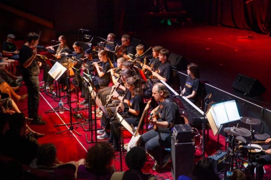 A large orchestra is playing on a stage in front of a crowd.