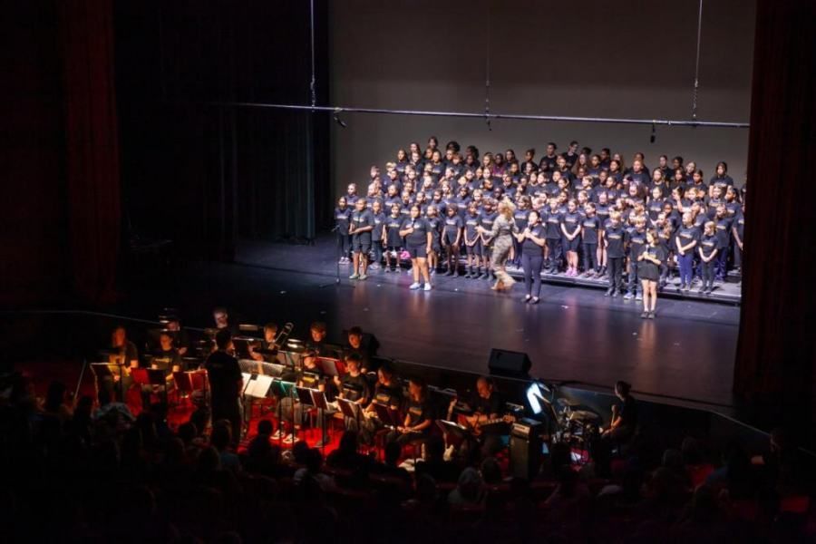A large choir and orchestra are performing on a stage.