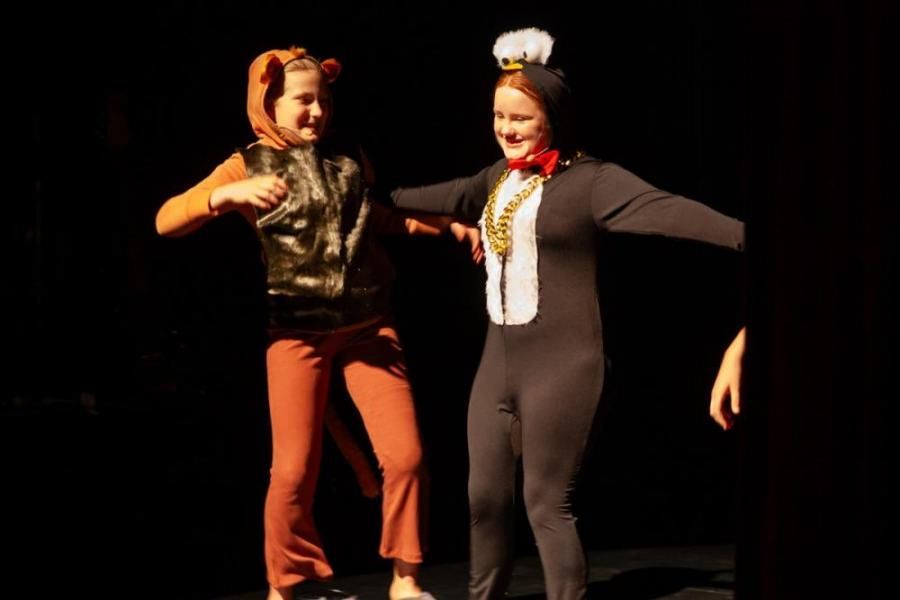 Two girls in cat in the hat costumes are dancing on a stage.