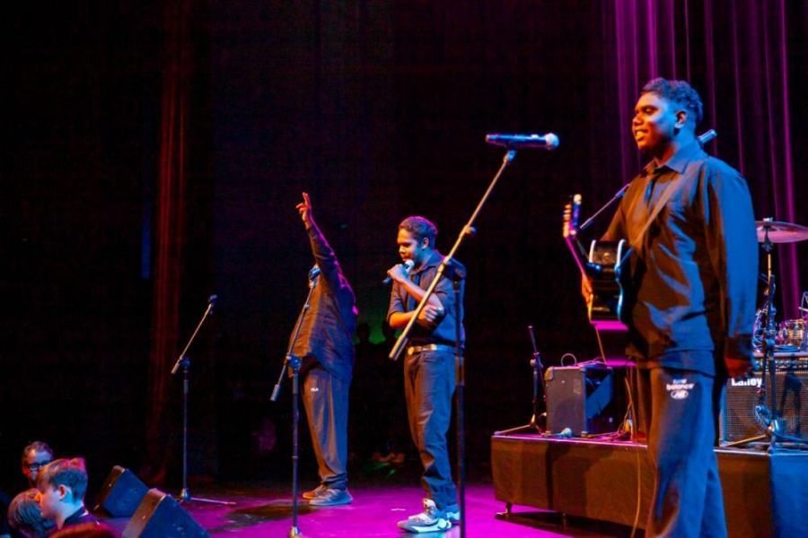 A group of men are singing into microphones on a stage.
