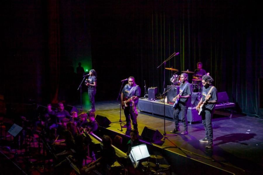 A group of men are playing instruments on a stage in front of a crowd.
