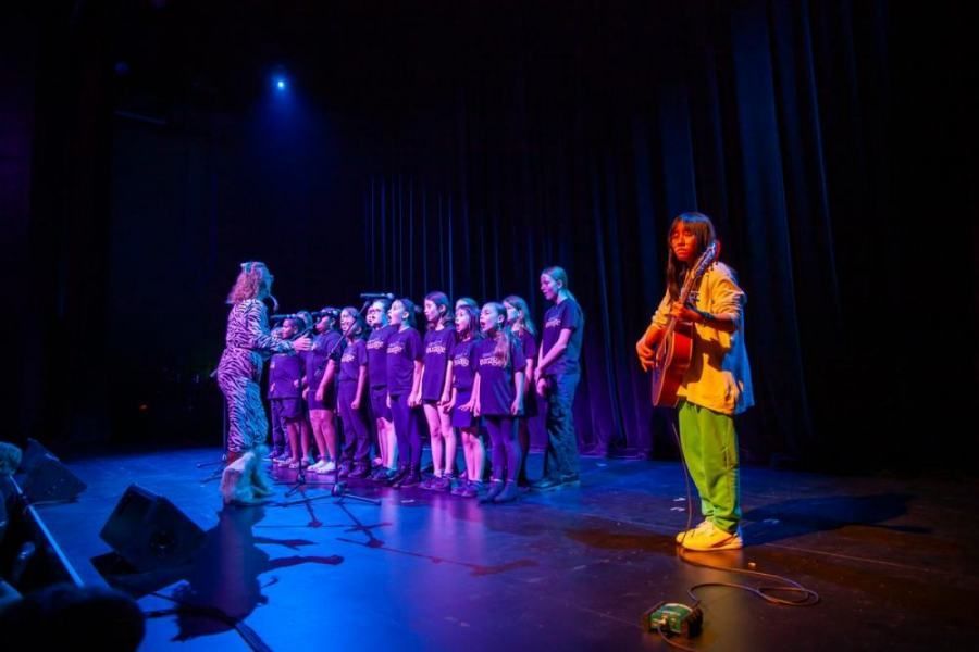 A man is playing a guitar in front of a group of people on a stage.
