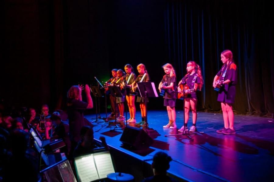 A group of young girls are standing on a stage playing guitars.