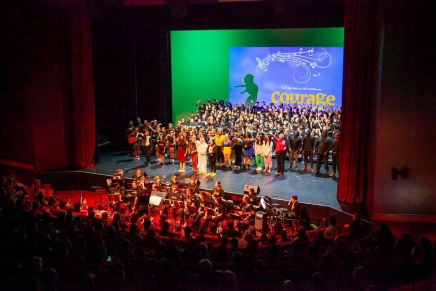 A large group of people are standing on a stage in front of a large screen that says courage.