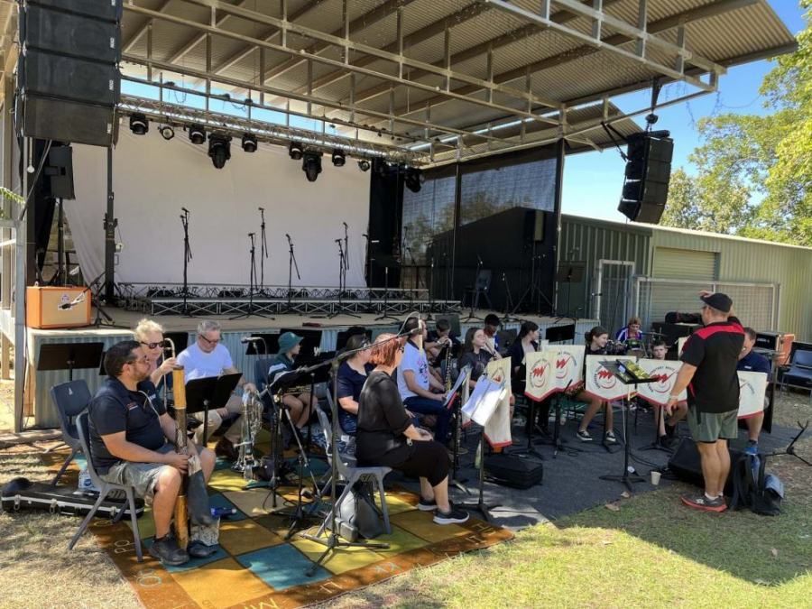 A group of people are sitting in front of a stage playing instruments.