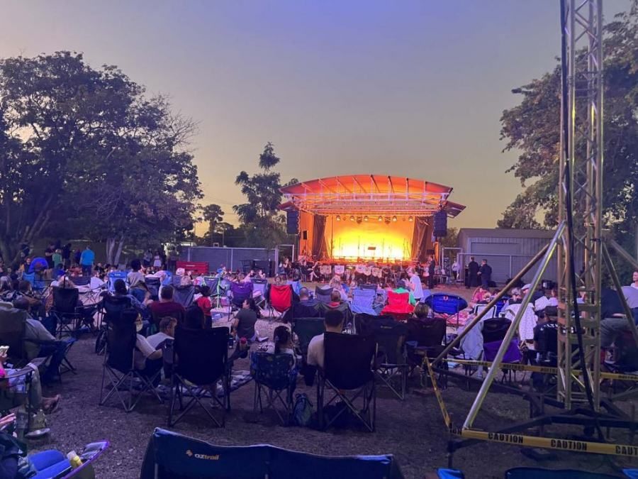 A crowd of people are sitting in chairs in front of a stage at a concert.
