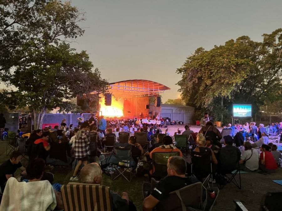 A crowd of people are sitting in chairs in front of a stage at a concert.