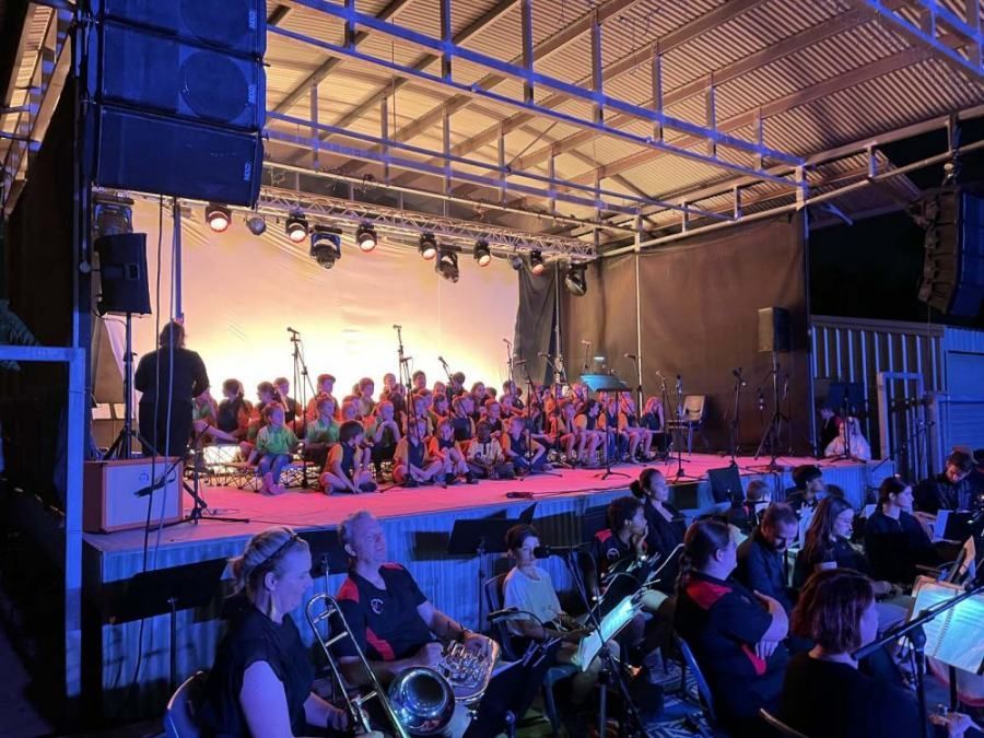 A large group of people are sitting on a stage playing instruments.