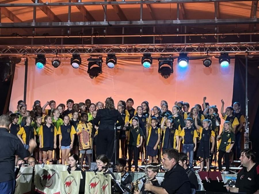 A large group of children are singing on a stage