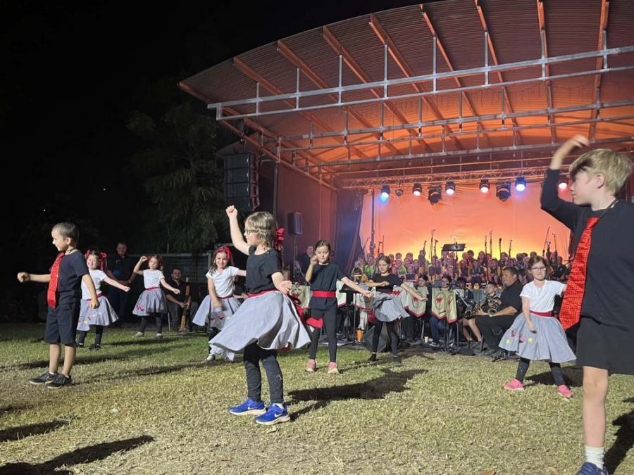 A group of children are dancing on a stage in front of a crowd.