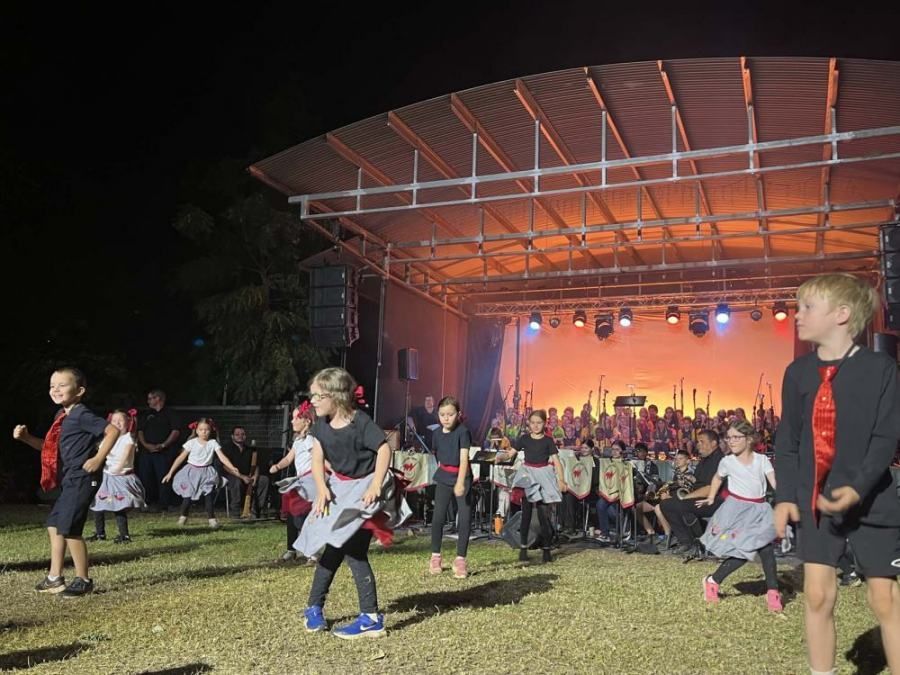 A group of children are dancing on a stage at night.