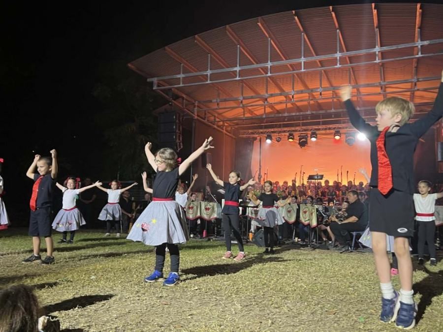 A group of children are dancing on a stage in front of a crowd.