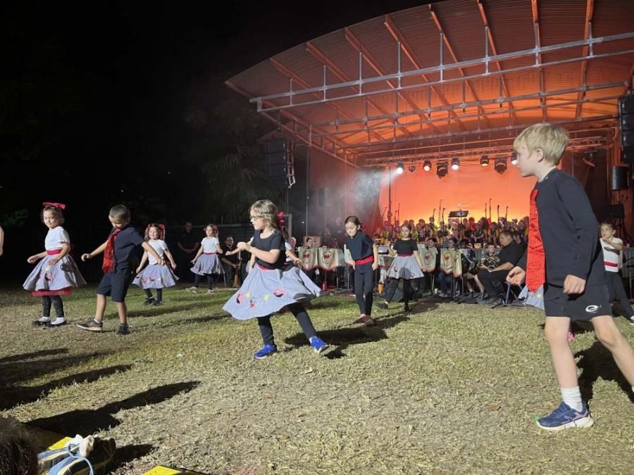 A group of children are dancing on a stage at night.