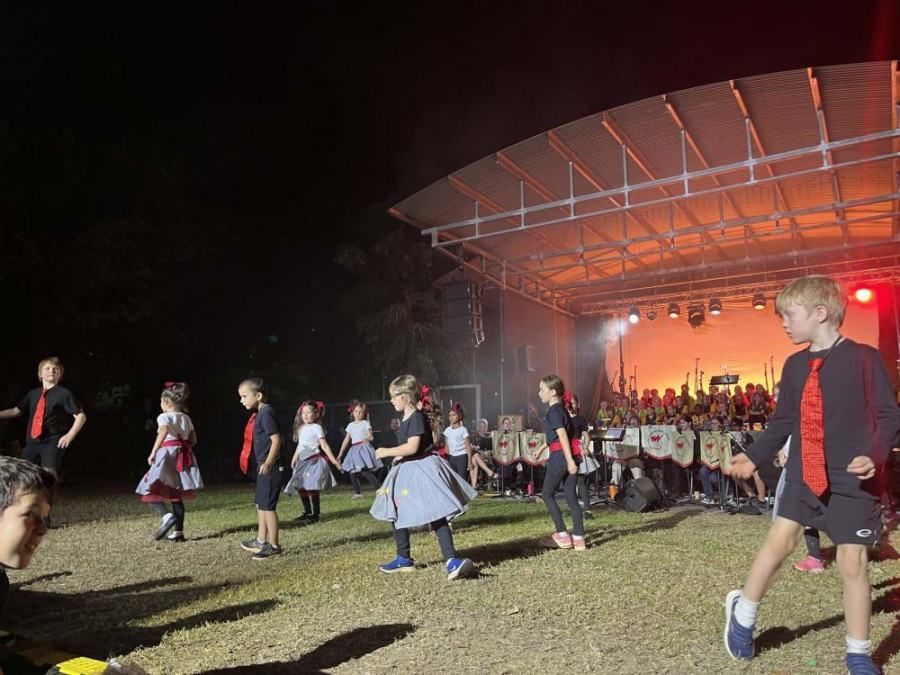 A group of children are dancing on a stage at night.