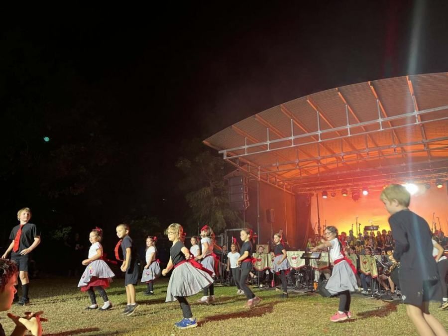 A group of children are dancing on a stage at night.