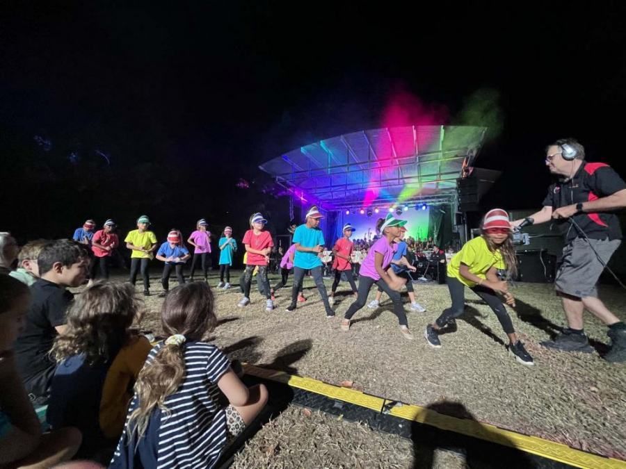A group of people are dancing on a stage at night.