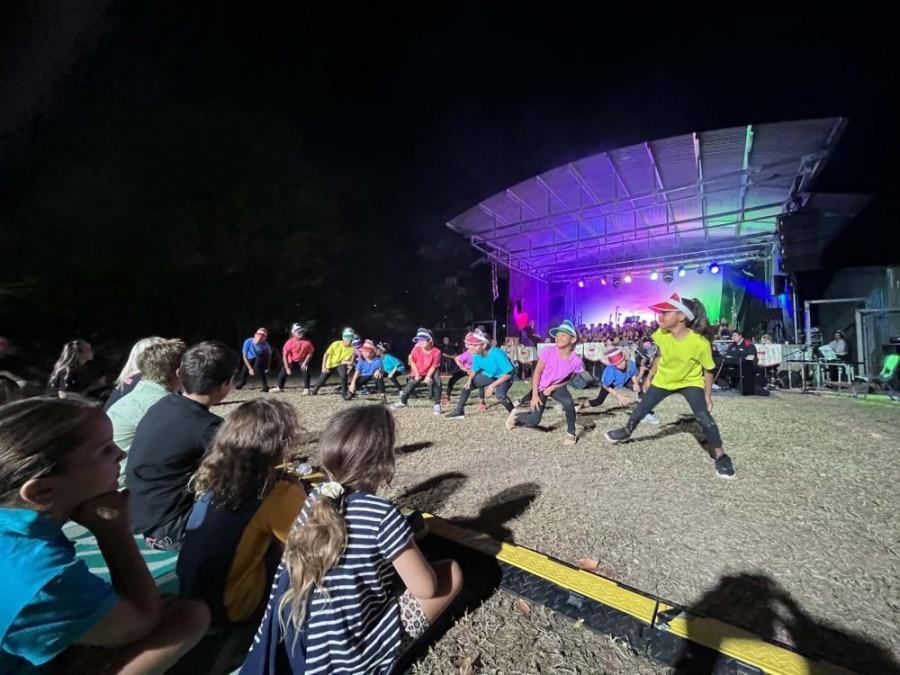 A group of people are watching a dance performance on a stage at night.