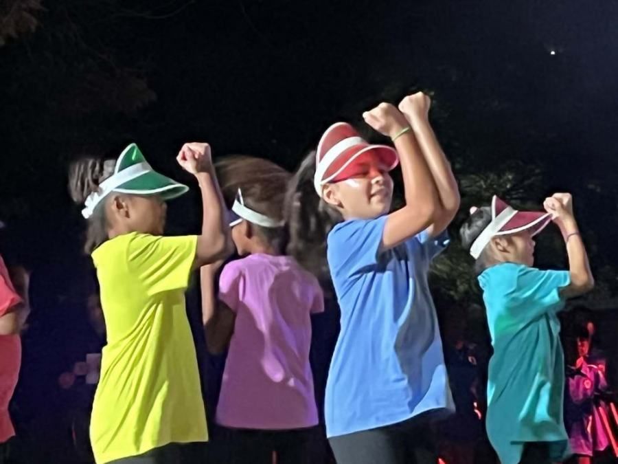 A group of children wearing visors are dancing together