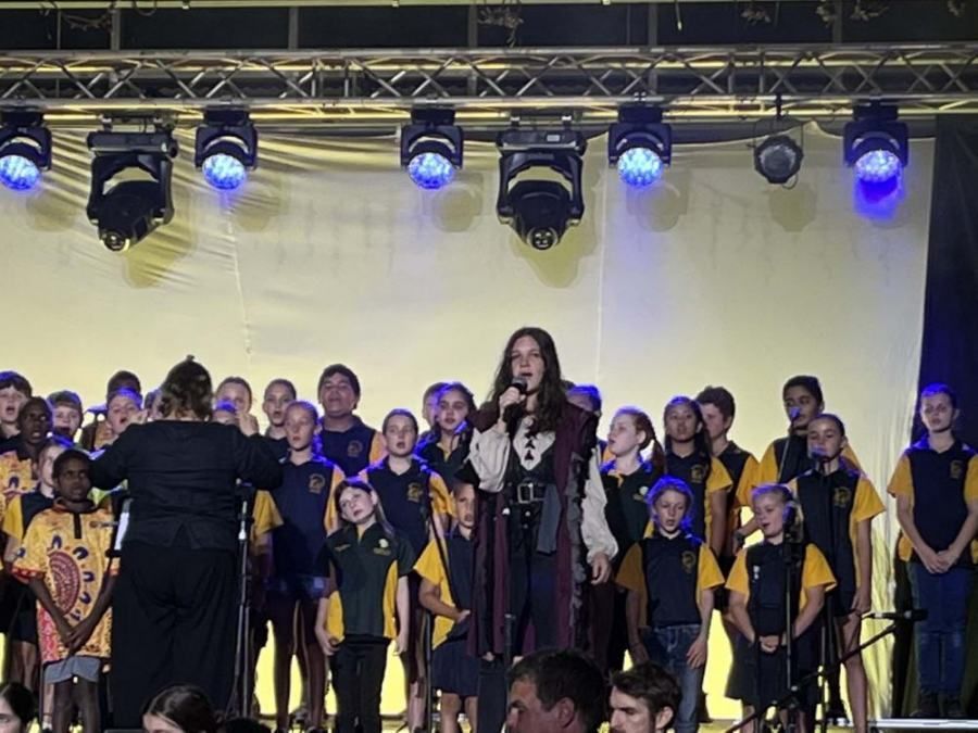 A man in a pirate costume is singing into a microphone in front of a choir.