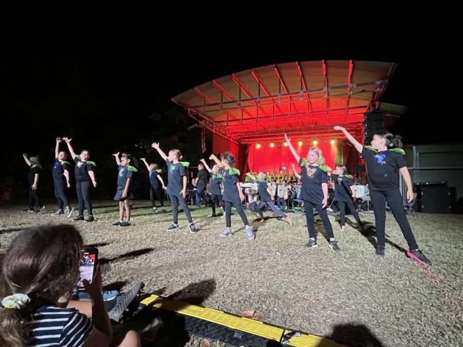 A group of children are dancing on a stage at night.