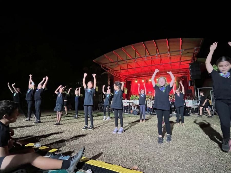 A group of children are dancing on a stage at night.