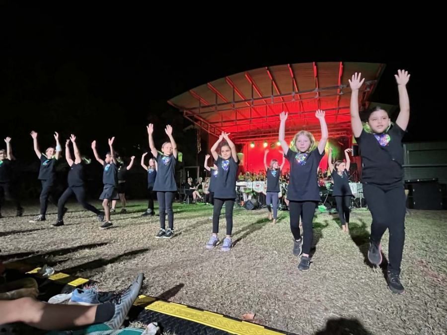A group of children are dancing on a stage at night.