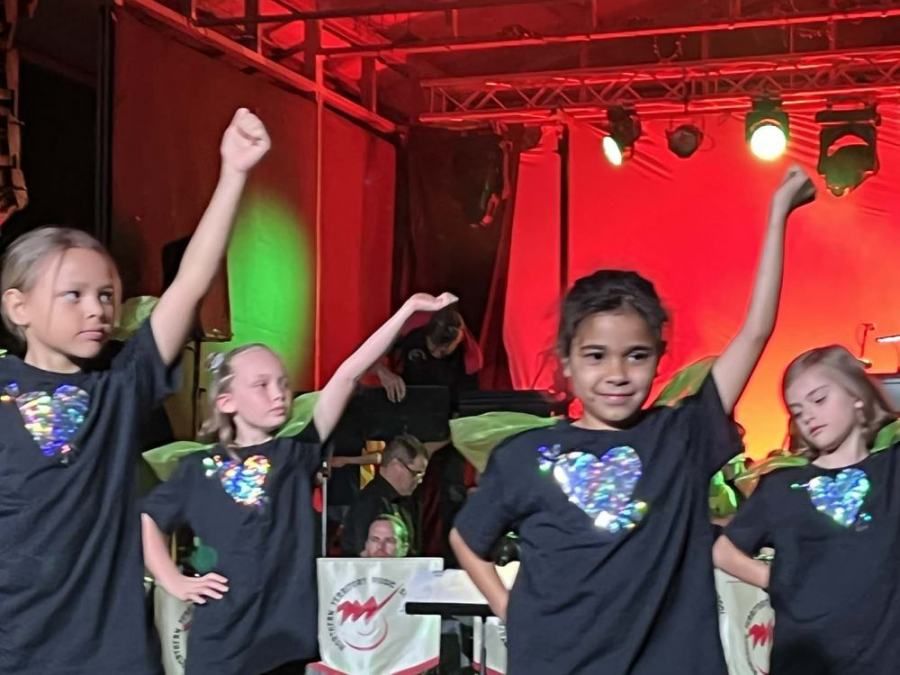 A group of young girls wearing black shirts with hearts on them