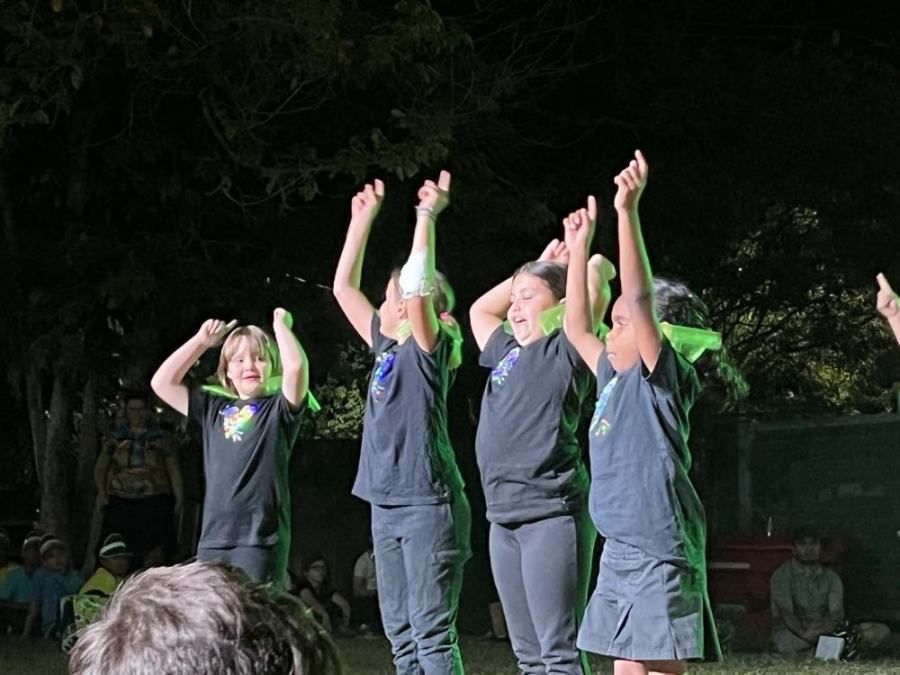 A group of children are standing in a line with their hands in the air.