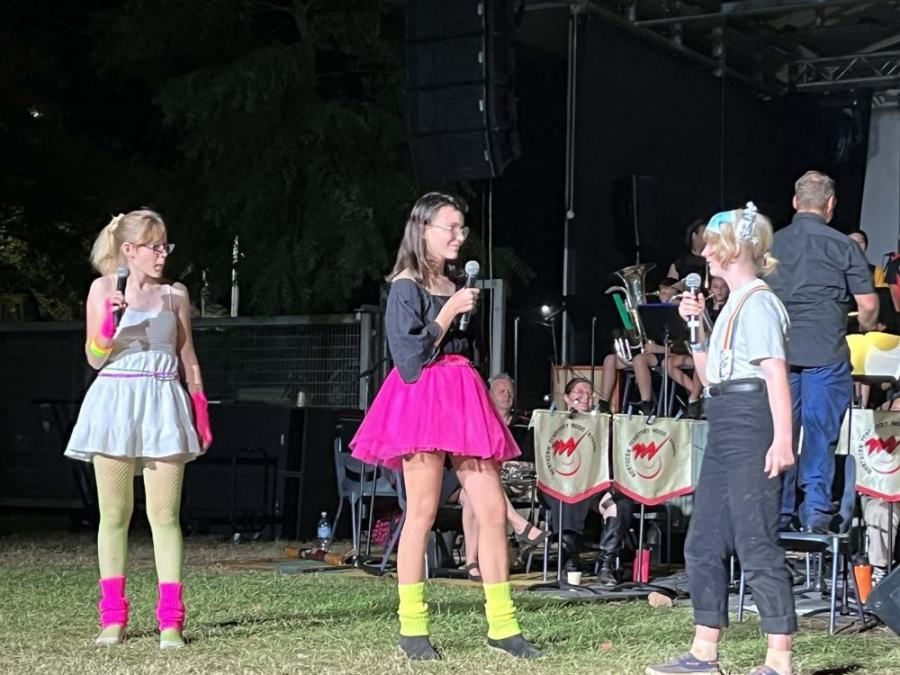 A group of girls are standing on a stage holding microphones.
