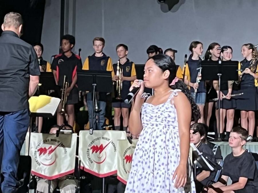 A girl singing into a microphone in front of a band