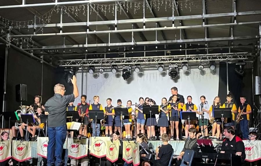 A man is leading a band on a stage.