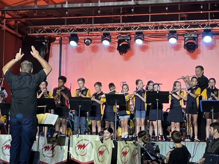 A man is leading a band on a stage.