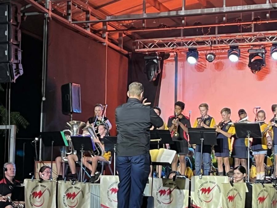 A man is leading a band on a stage.