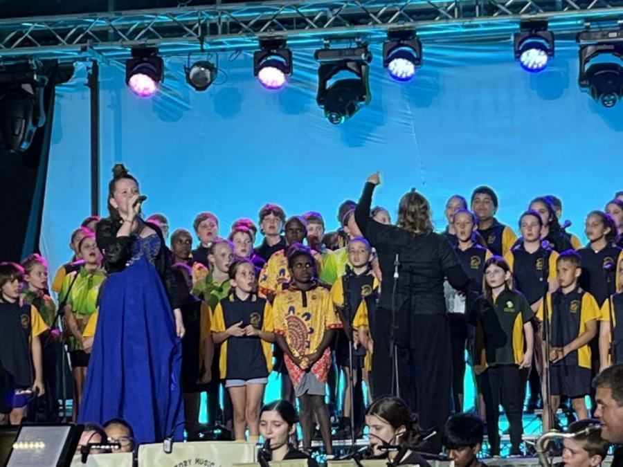 A choir is performing on a stage with a conductor.