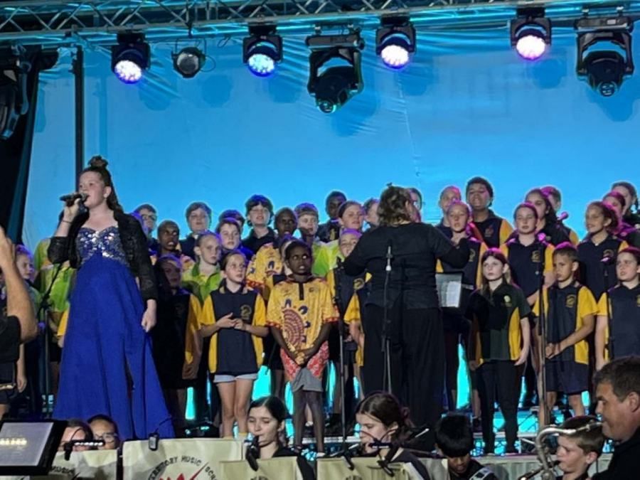 A woman singing into a microphone in front of a choir