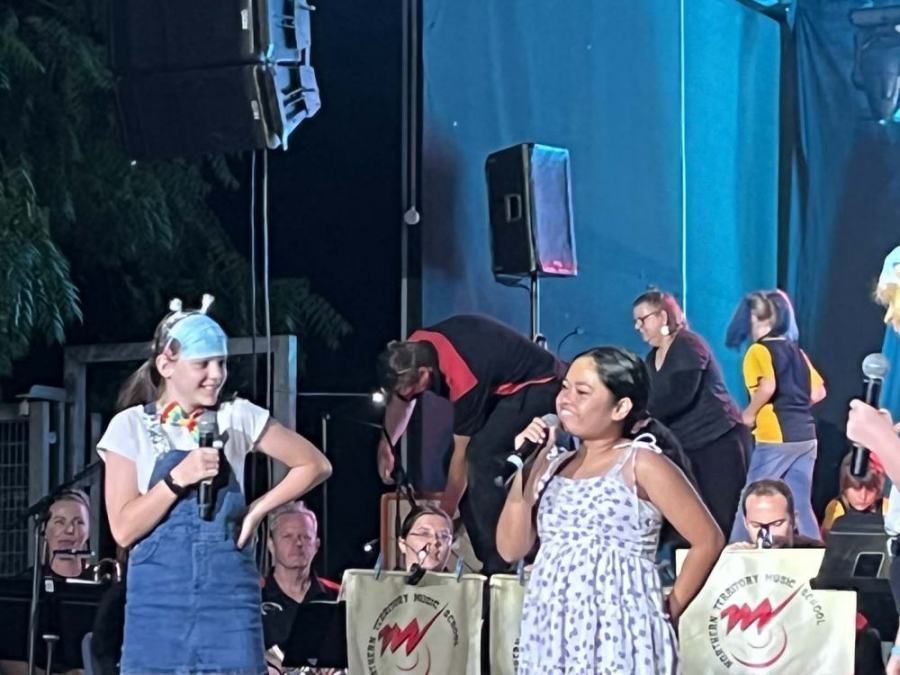 Two young girls singing into microphones on a stage