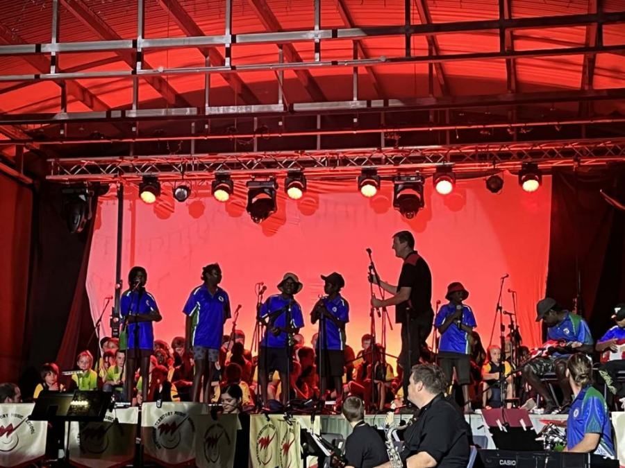 A group of people playing instruments on a stage with a red background