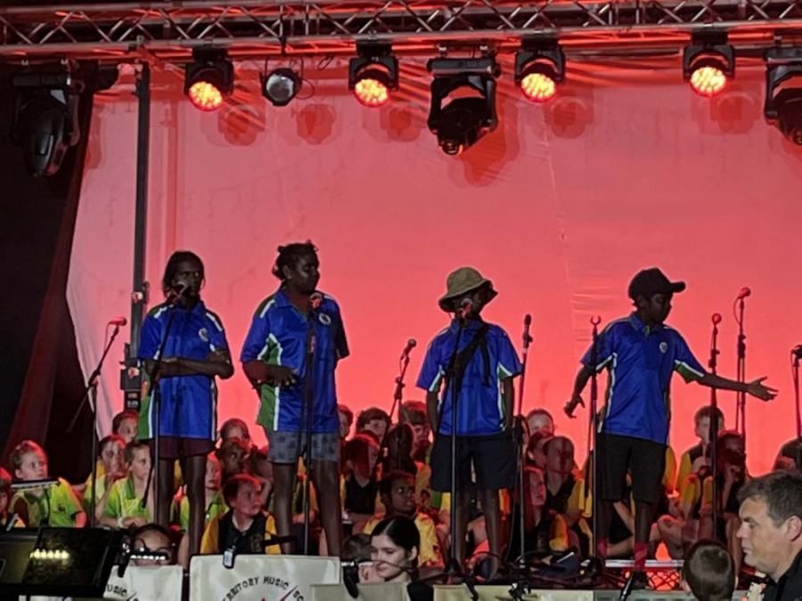 A group of children are singing into microphones on a stage