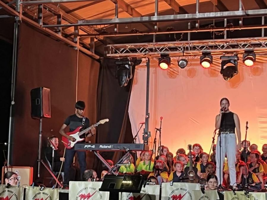 A man playing a guitar and a woman singing on a stage
