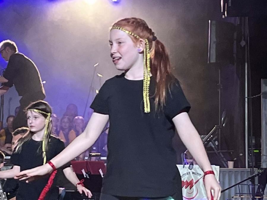 A girl in a black shirt is dancing on a stage