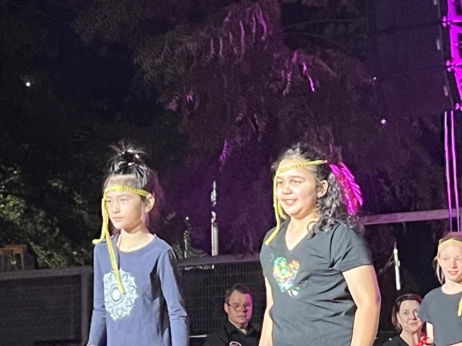Two young girls are standing next to each other on a stage.