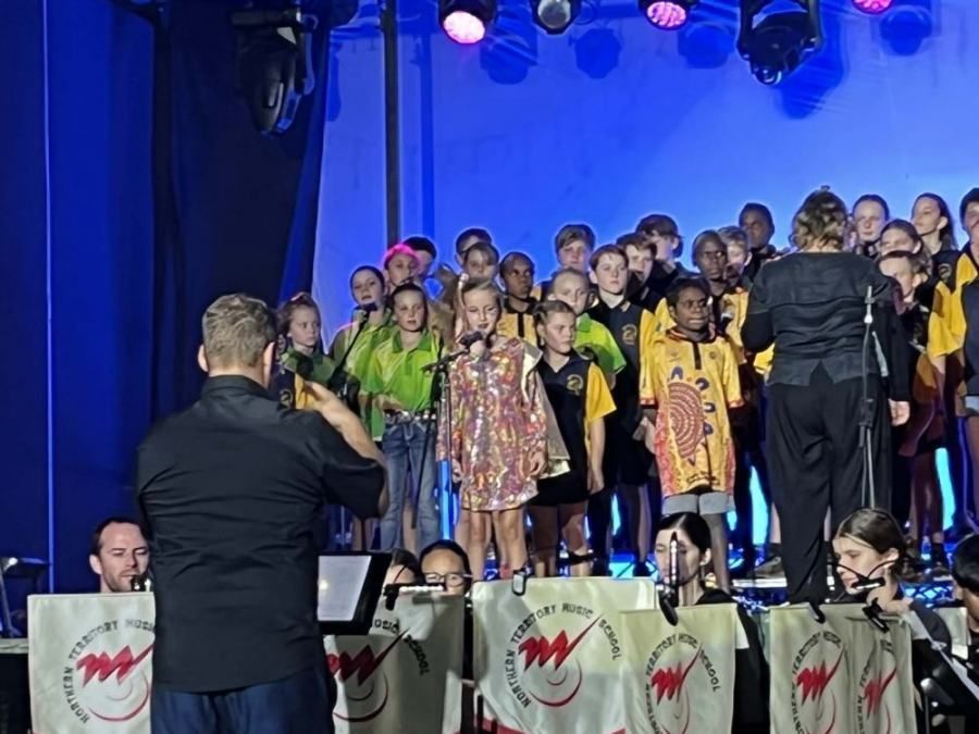 A man is taking a picture of a choir on stage
