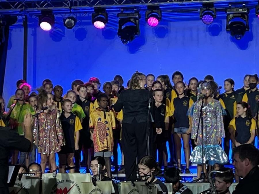 A large group of children are singing on a stage