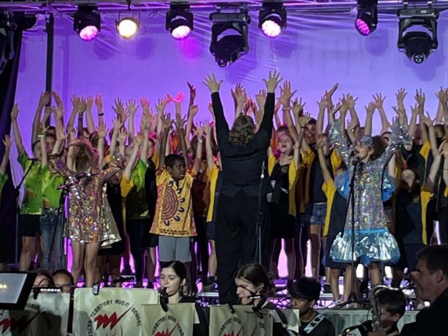 A choir is performing on stage with their hands in the air