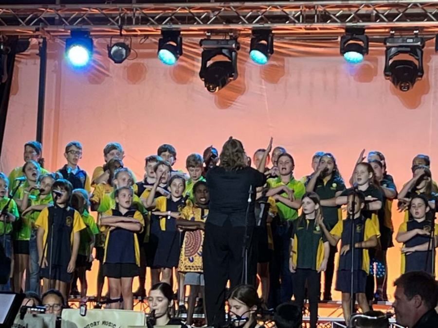 A group of children are singing in a choir on a stage