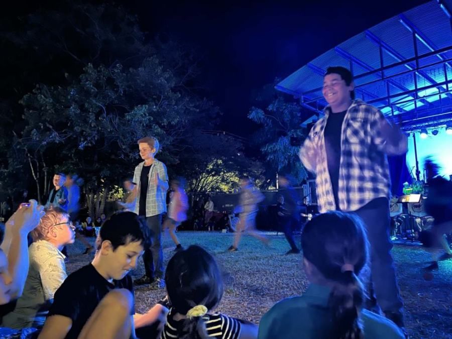 A group of people are standing in front of a stage at night.