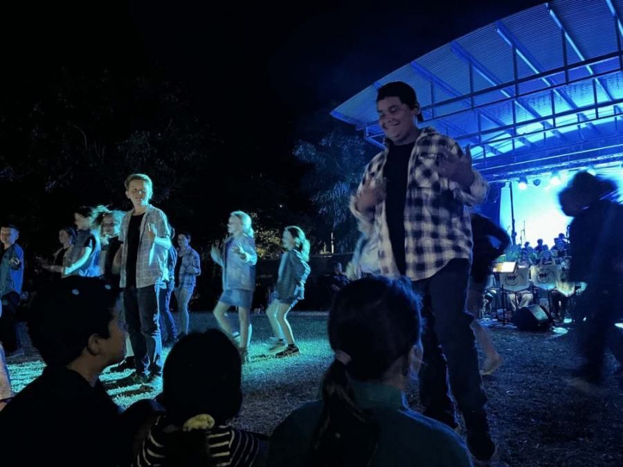 A group of people are dancing on a stage at night.