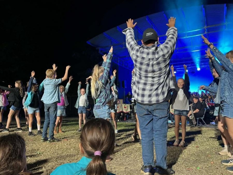 A group of people are standing in a field with their arms in the air.