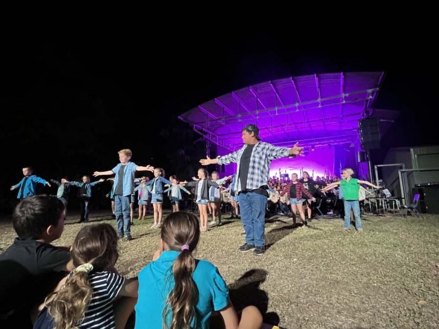 A group of people are dancing on a stage at night.