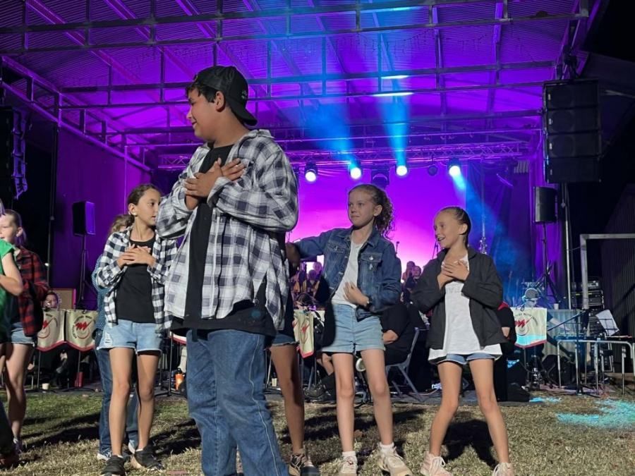 A group of children are dancing on a stage at a concert.